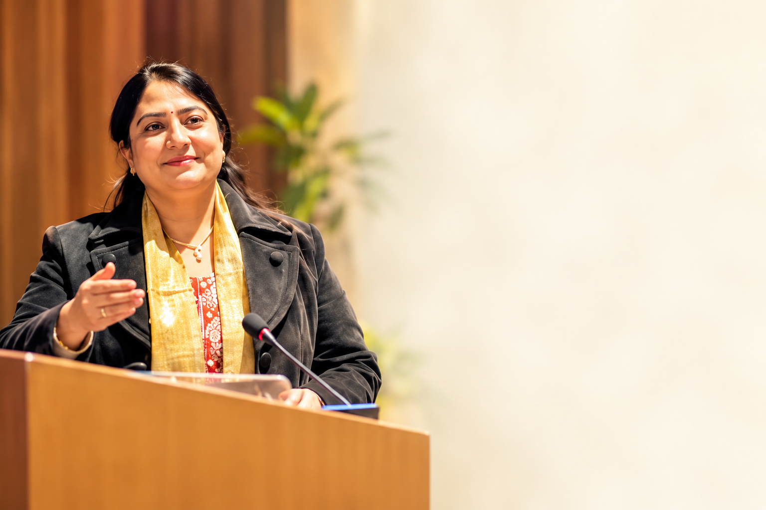 Reference-inspired portrait of Aditi Dadhich speaking at a podium